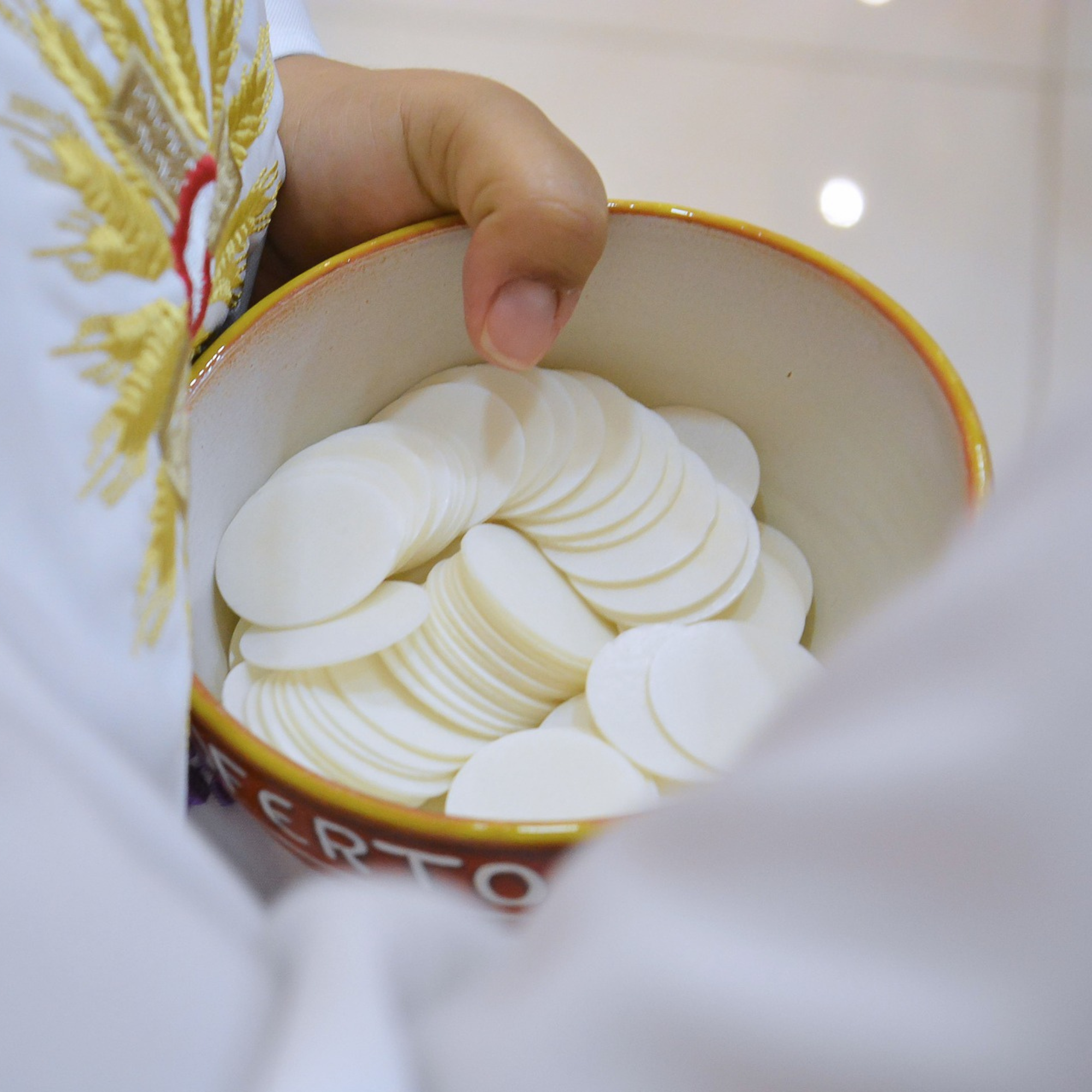 Patena z komunikantami w dłoniach kapłana